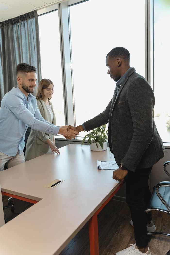 Professional handshake between colleagues in a modern office setting.