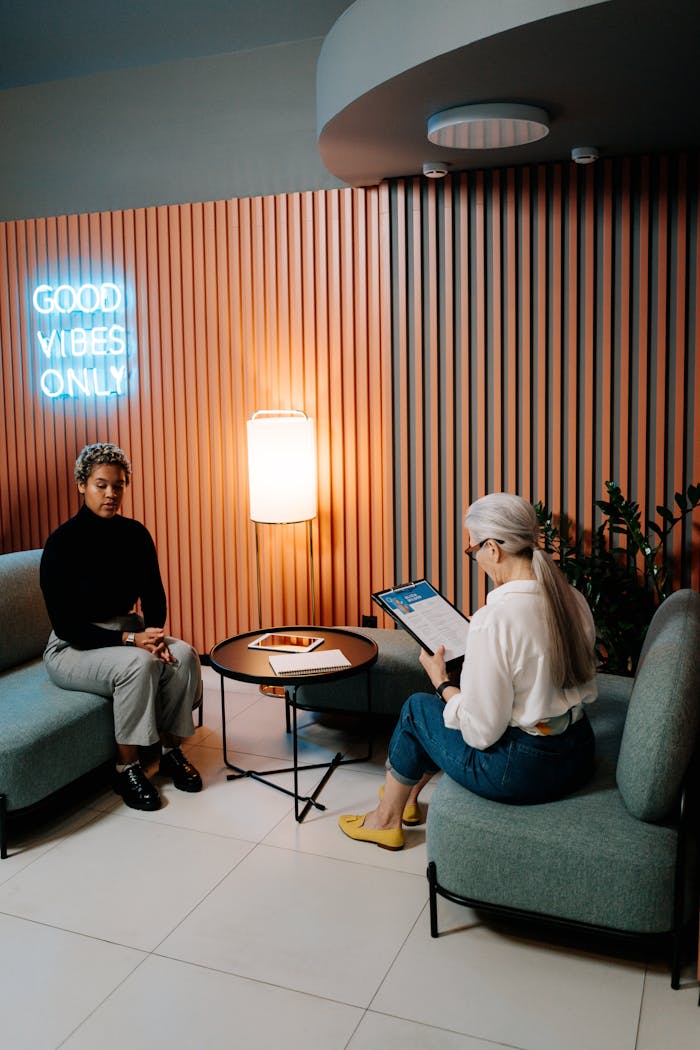 Two professional women engaged in a business meeting in a modern office lounge.